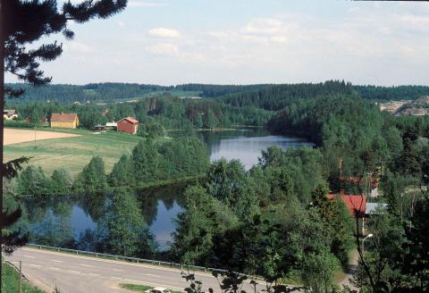 picture of lake with farm and tree line and homes and road